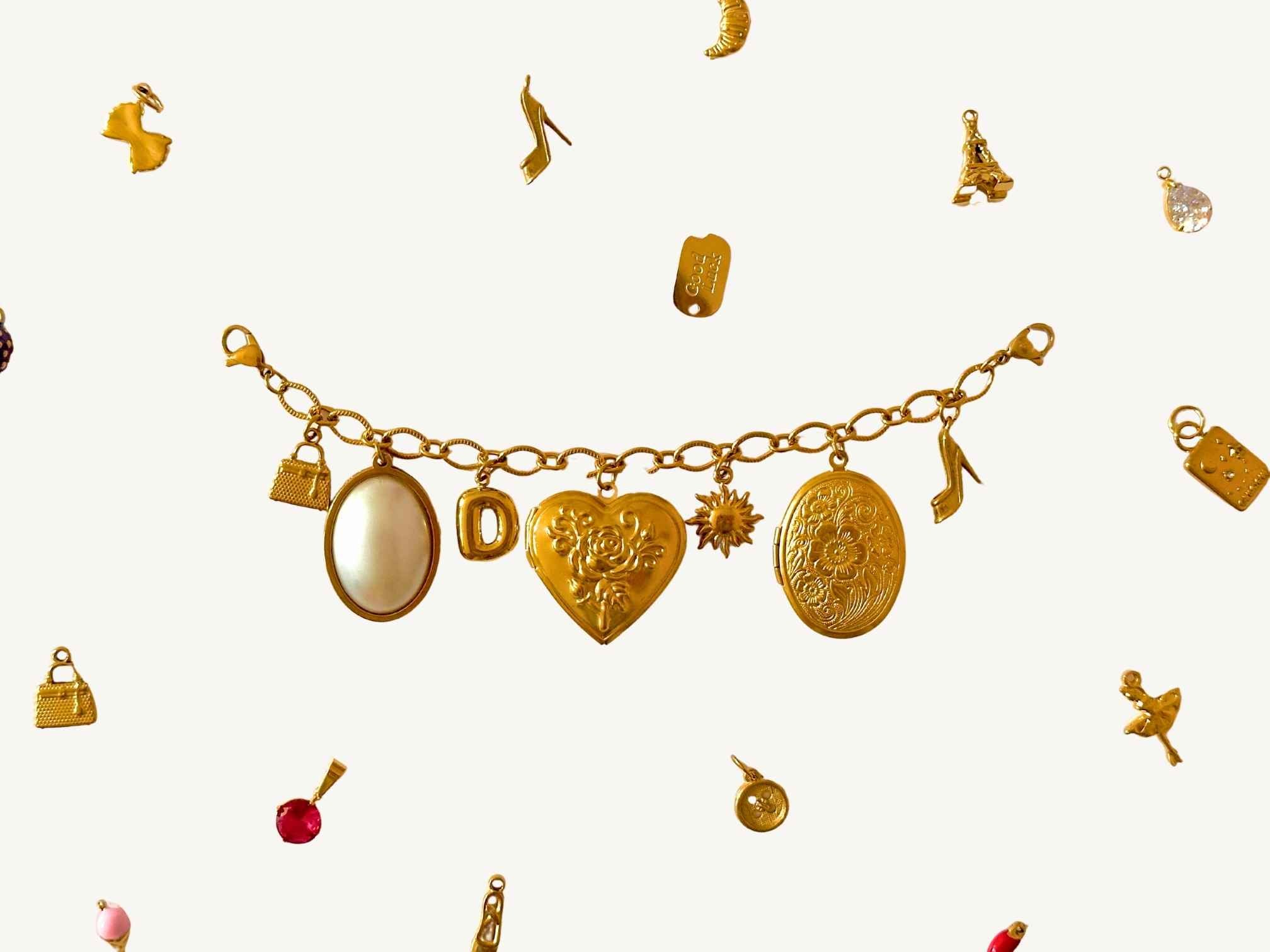 Goldenes Charm Charivari mit verschiedenen Anhängern auf beigem Hintergrund