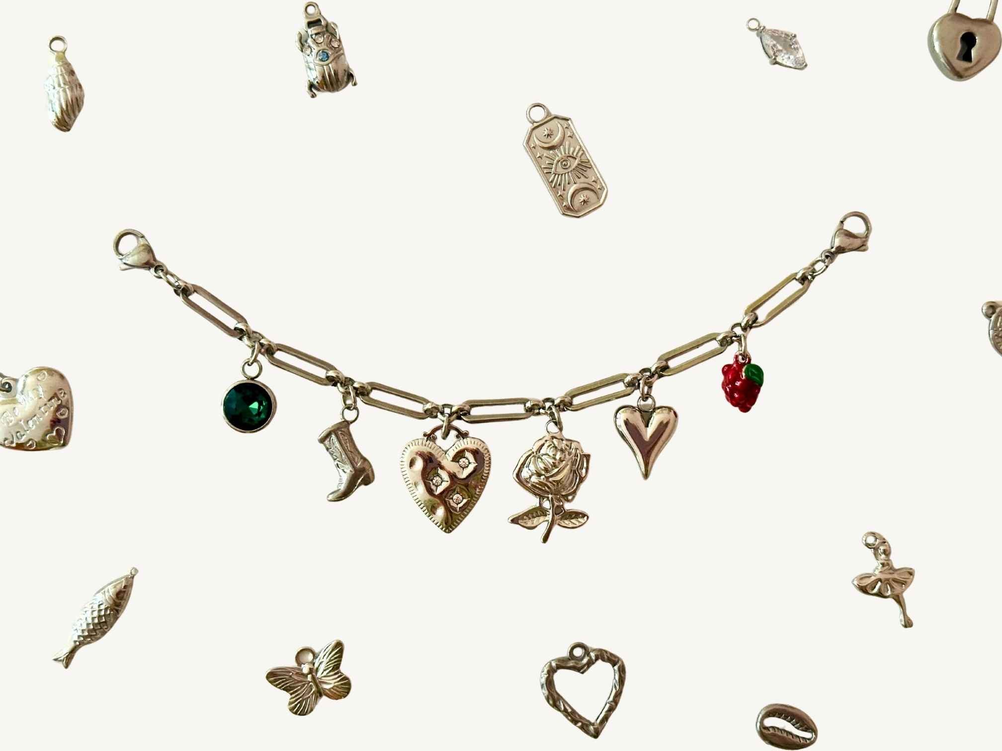 Silbernes Charm Charivari mit verschiedenen Anhängern auf beigen Hintergrund