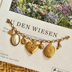 Goldenes Charm Charivari mit verschiedenen Anhängern auf dekorativen Hintergrund