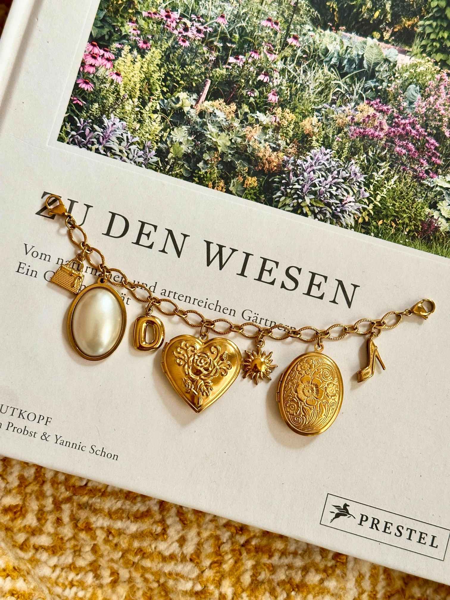 Goldenes Charm Charivari mit verschiedenen Anhängern auf dekorativen Hintergrund