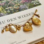 Goldenes Charm Charivari mit verschiedenen Anhängern auf dekorativen Hintergrund