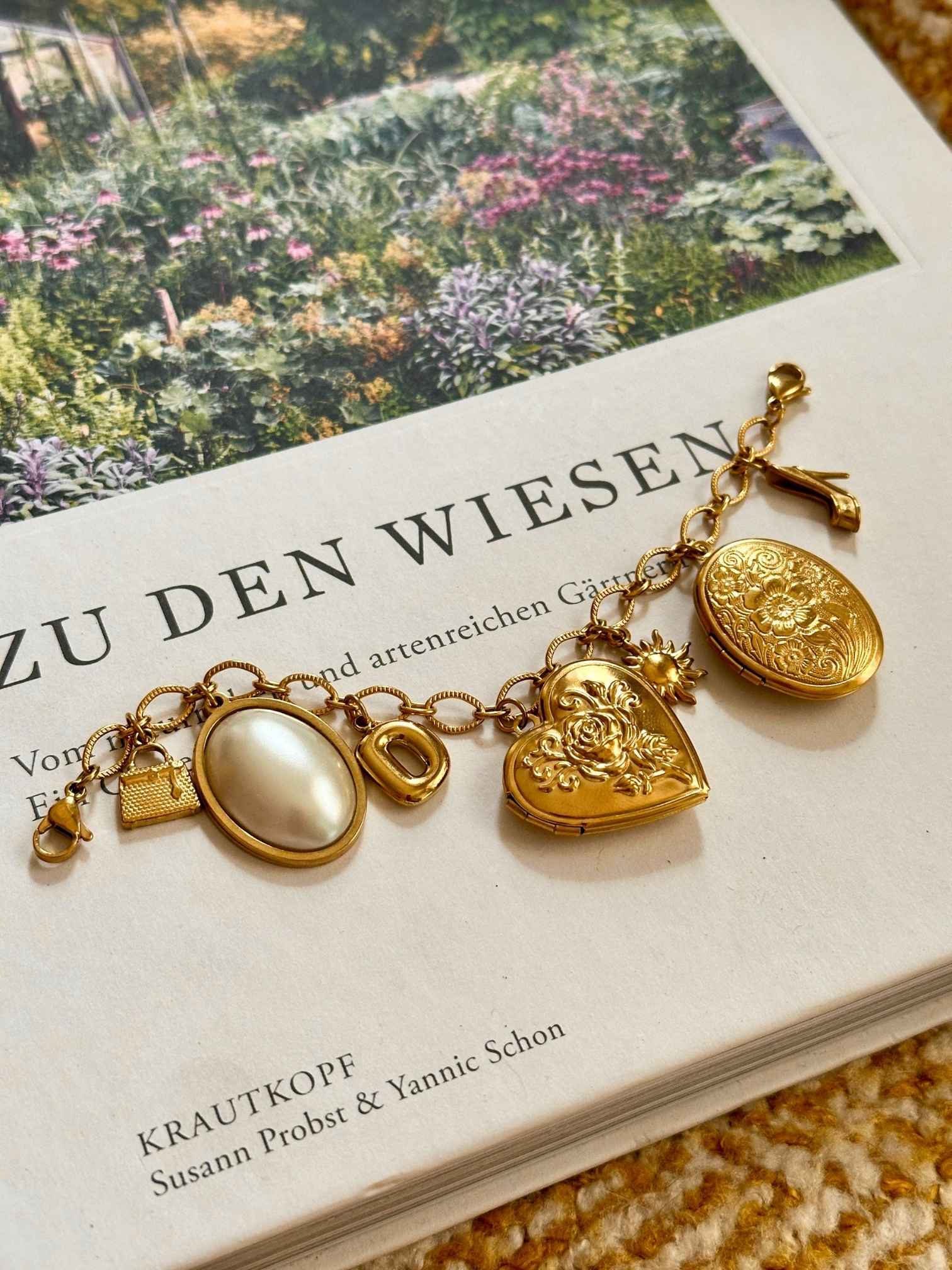 Goldenes Charm Charivari mit verschiedenen Anhängern auf dekorativen Hintergrund