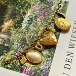 Goldenes Charm Charivari mit verschiedenen Anhängern auf dekorativen Hintergrund