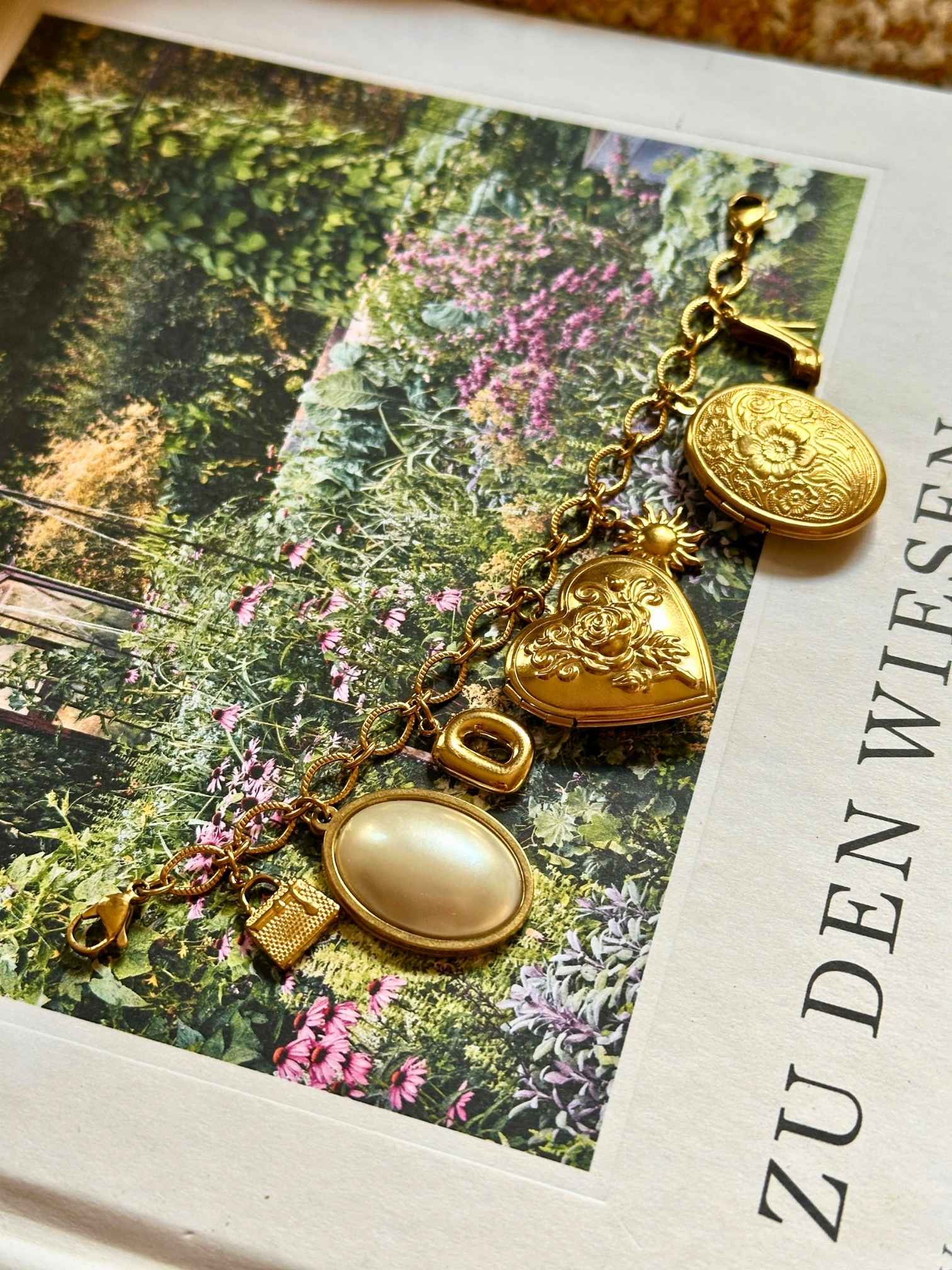 Goldenes Charm Charivari mit verschiedenen Anhängern auf dekorativen Hintergrund