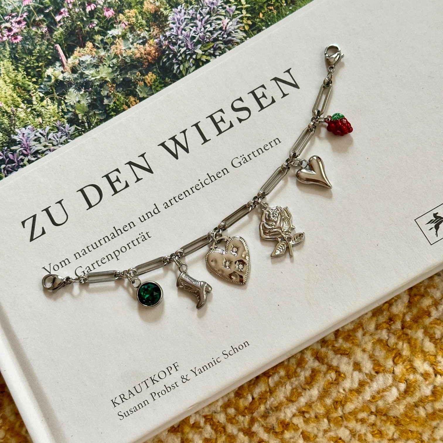 Silbernes Charm Charivari mit verschiedenen Anhängern auf dekorativen Hintergrund