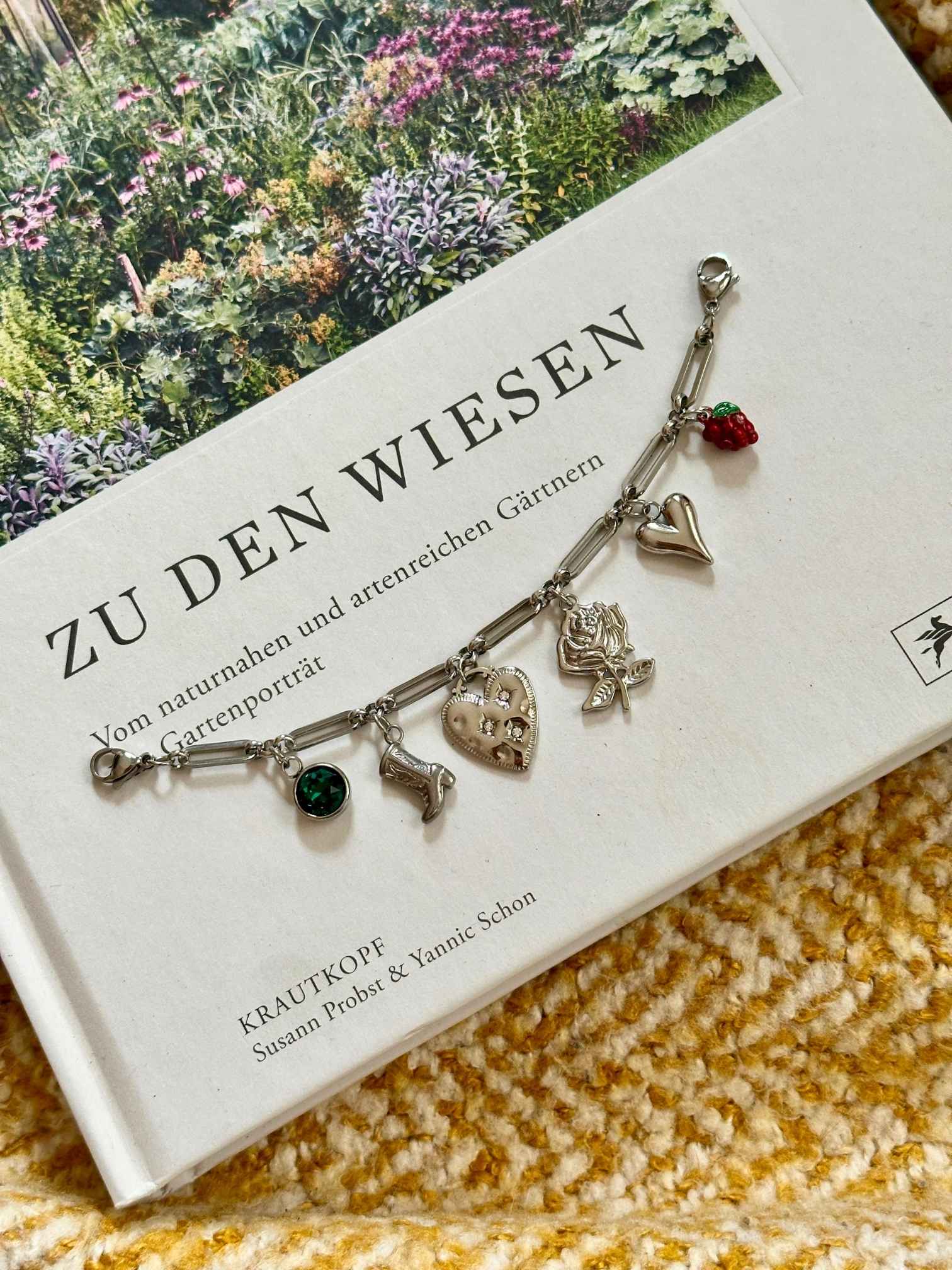 Silbernes Charm Charivari mit verschiedenen Anhängern auf dekorativen Hintergrund