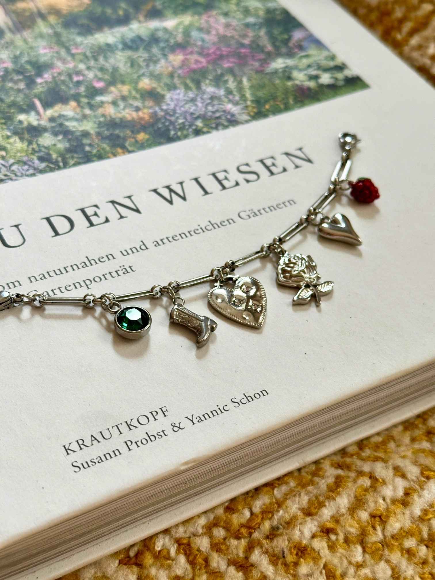 Silbernes Charm Charivari mit verschiedenen Anhängern auf dekorativen Hintergrund