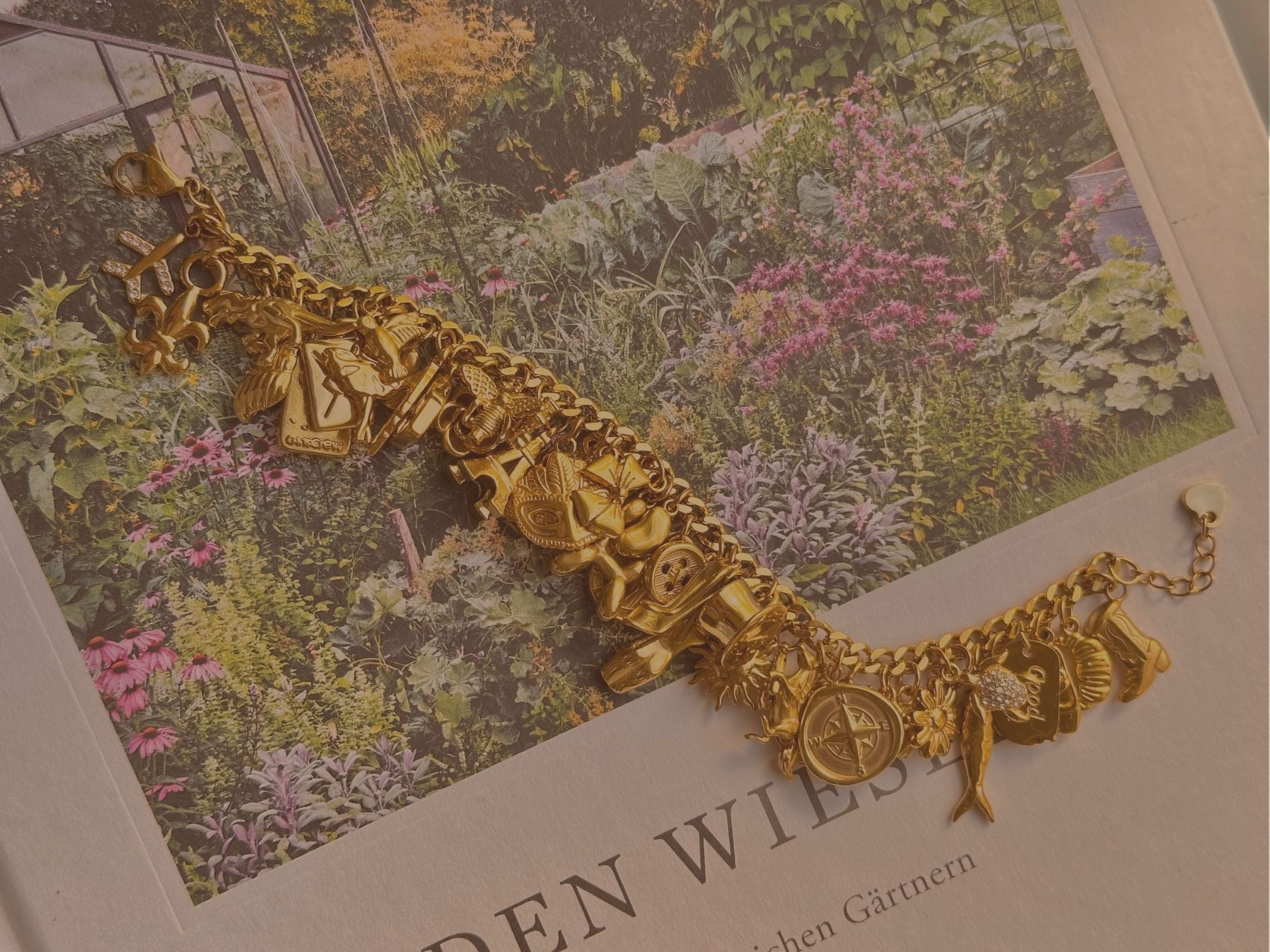 Goldenes Charm Armband mit vielen verschiedenen Anhängern auf dekorativen Hintergrund