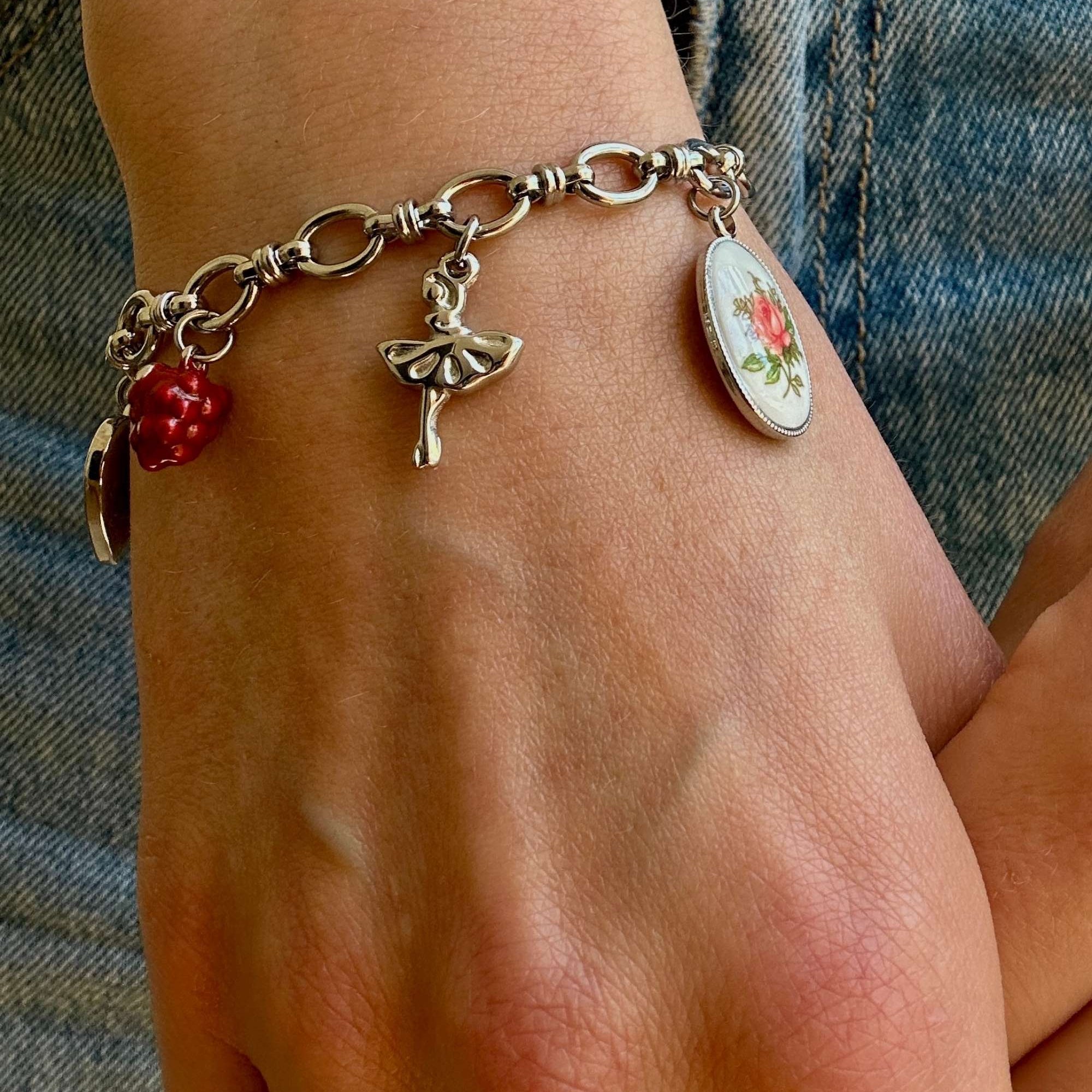 Silberfarbenes Miss Colette Charm Armband mit Herzschloss, Ballerina, Blumenanhänger und Vintage Details. Femininer Schmuck.